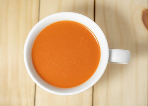 Hot milk tea in a white cup on wooden background