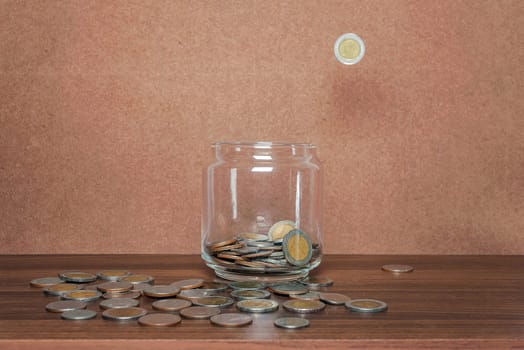 Save money and account banking for finance business concept, Coin in bottle and fall on brown background
