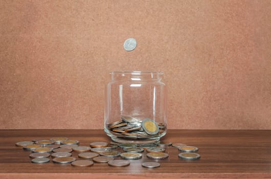 Save money and account banking for finance business concept, Coin in bottle and fall on brown background