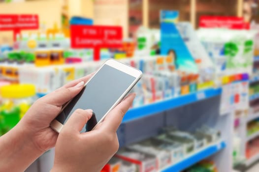 Pharmacy and drugstore concept, Hand women using smart phone in pharmacy store on blurred background