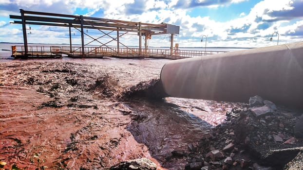 The industrial wastewater is discharged from the pipe into the water.