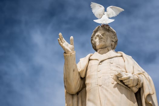 White bird sitting on top of ancient statue of Dionysios Solomos in Zakythos Town square, Greece