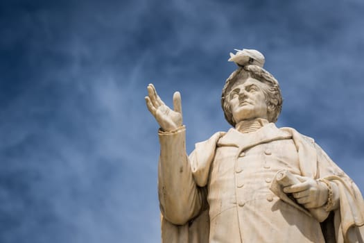 White bird sitting on top of ancient statue of Dionysios Solomos in Zakythos Town square, Greece