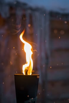 Fire burning inside metal torch in front of a wooden shed in a Sami people village, northern Norway