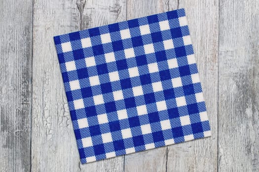 Empty table background. Top view of a empty blue and white checkered kitchen cloth, textile, tablecloth or napkin on a rustic bright gray table. Template for food and product display montage. Macro.