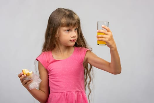 The girl intently looks at a glass of juice