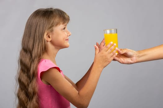 The hand holds out a glass of orange juice