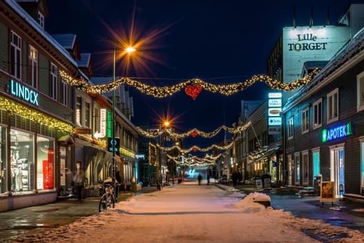 Tromso, Norway -  December 2018 : Christmas lights and decorations hanging between buildings in the centre of Tromso town