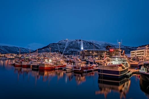 Tromso, Norway -  December 2018 : Boats in port and harbour in Tromsoysundet strait in Tromso in winter at night