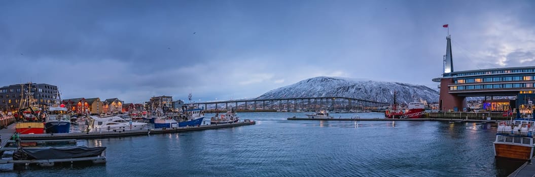Tromso, Norway -  December 2018 : Port and harbour with famous Tromso Bridge across Tromsoysundet strait in the background