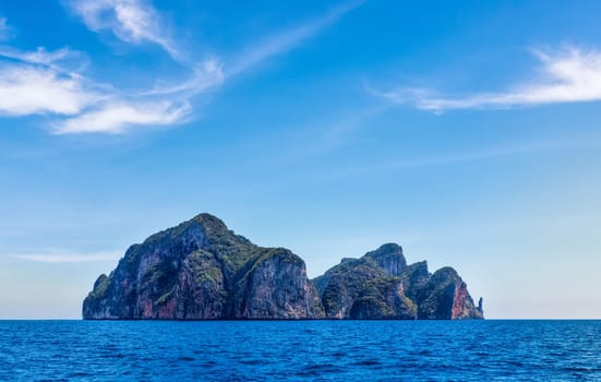 View from sea on entire Phi Phi Lay island with tall cliffs and mountains, blue shy and white clouds, Thailand