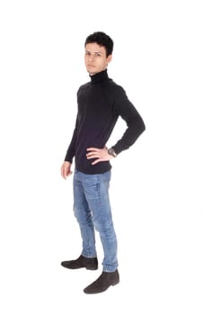 A good looking young man in black sweater and jeans standing in the.studio, resting and smiling, isolated for white background.