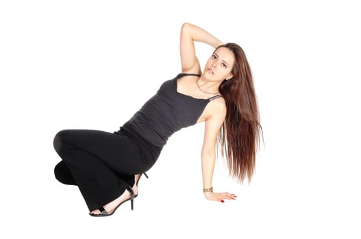 A beautiful young woman in a black outfit and long brunette hair.sitting on the floor, hand on her head, isolated for white background.