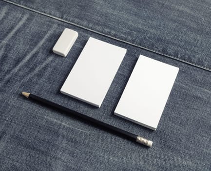 Blank name cards, pencil and eraser on denim background. Copy space for placing your design.