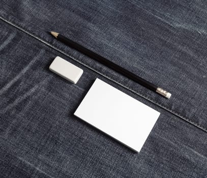 Photo of blank business card, pencil and eraser. Blank stationery set on denim background.