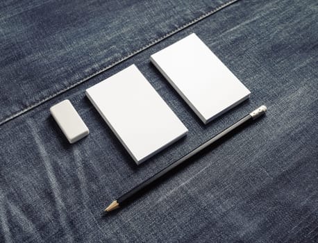 Photo of blank white business cards stacks, pencil and eraser on denim background. Stationery mock up.
