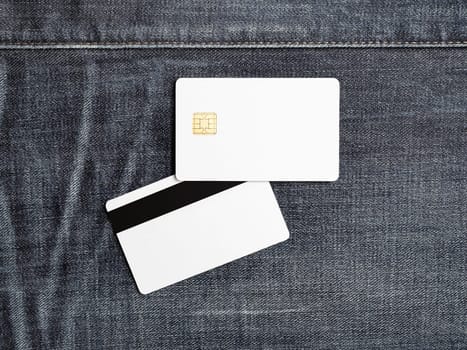 Photo of blank plastic bank cards on denim background. White credit cards. Front and back view. Template for placing your design. Flat lay.