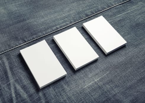 Photo of blank name cards on denim background. Mockup of three business cards.