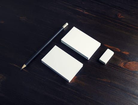 Photo of blank name cards, pencil and eraser on dark wood table background.