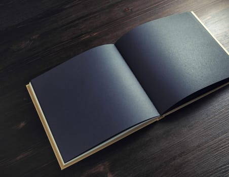 Photo of blank black brochure mock up on dark wood table background. Copy space for text.
