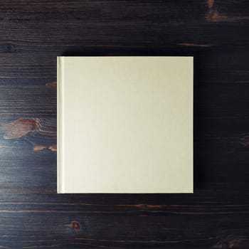 Photo of blank hardcover brochure on dark wood table background. Copy space for text. Flat lay.