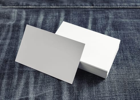 Photo of blank white business cards on denim background.
