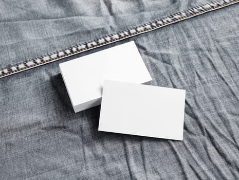 Blank white paper business cards on gray denim background.