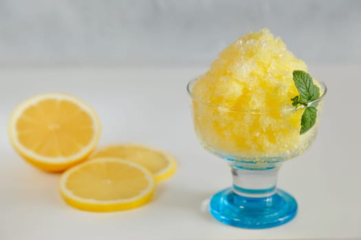 Japanese dessert kakigori lemon in a glass bowl and lemon slices in the background