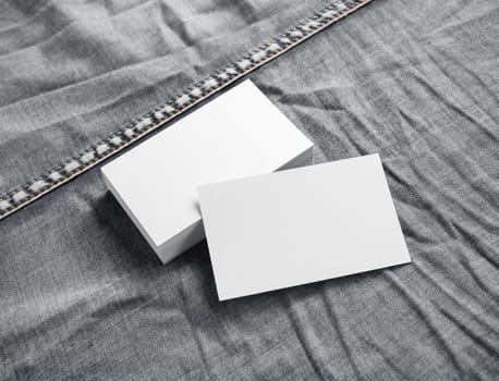 Blank white business cards on gray denim background.