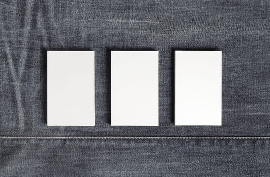Mockup of three blank vertical business cards on gray denim background. Copy space for text. Flat lay.