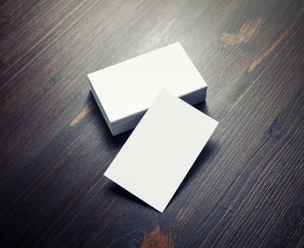 Blank white paper business cards on dark wood table background. Copy space for text.
