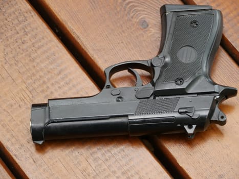illegal black handgun on wooden table close to
