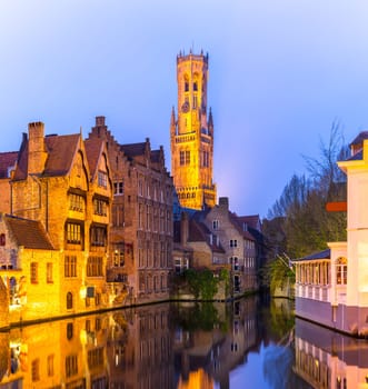 Historic medieval buildings along a canal in Bruges, Belgium at dusk.