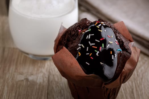 Chocolate cake in baking paper and a glass of milk in the background