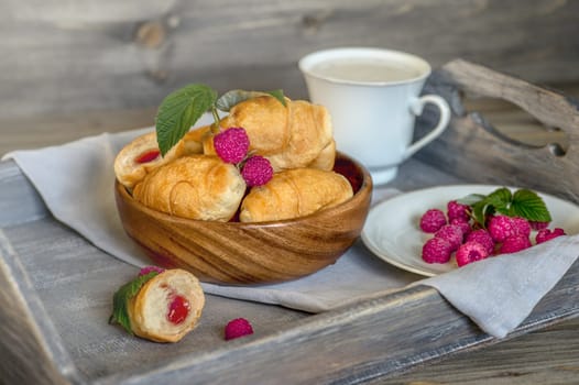 Croissants, a cup with kefir and ears of grain on a wooden tray. The concept of a wholesome breakfast