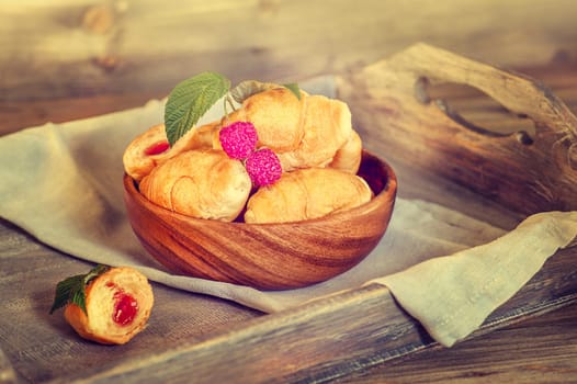 Croissants with raspberries on a wooden tray. The concept of a wholesome breakfast