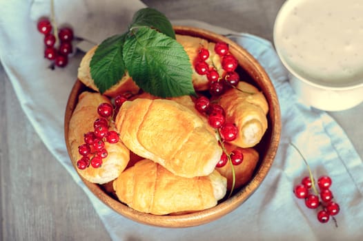 Croissants with currant berries on a wooden tray. The concept of a wholesome breakfast