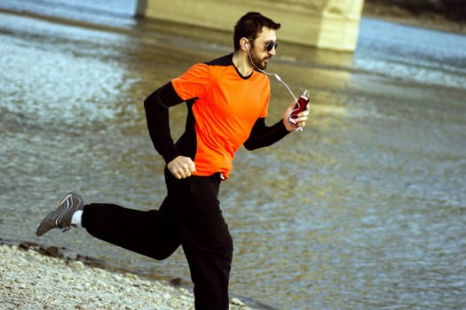 The jogger is running quickly with earphones at riverside.