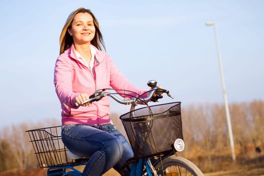 Attractive smiling woman is on bicycle outdoors, active life concept.