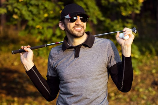 Portrait of smiling handsome confident golfer outdoors in nature.