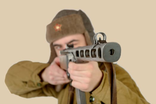 a young Soviet soldier fires with a machine gun on white background