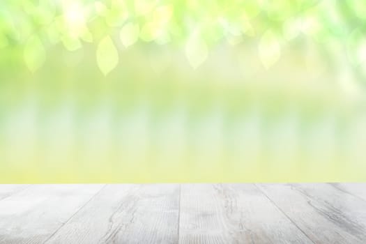 Empty table top summer background. Empty rustic wooden bright table top in front of a beautiful abstract light green spring background. Template for your product display montage.