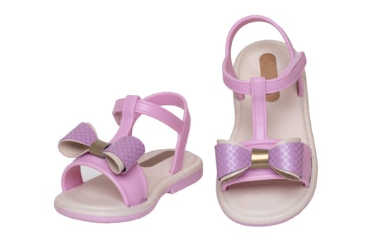Pink sandals isolated. Close-up of cute pink sandals with a bow for the little girl isolated on a white background. Trendy summer shoe fashion for children. Macro.