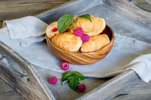 Croissants with currant berries on a wooden tray. The concept of a wholesome breakfast