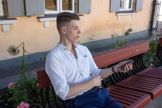 Outdoor portrait of modern young man with mobile phone in the bench