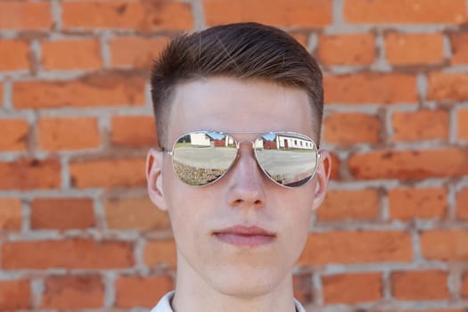 Portrait of a casually dressed young businessman standing against a brick wall