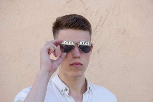 portrait of a handsome man dressed in white shirt against yellow wall