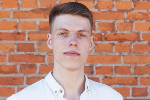 Portrait of a casually dressed young businessman standing against a brick wall
