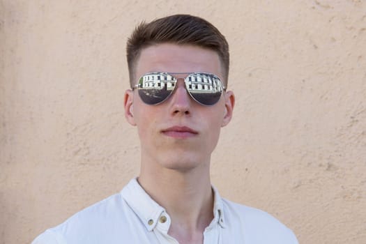 portrait of a handsome man dressed in white shirt against yellow wall