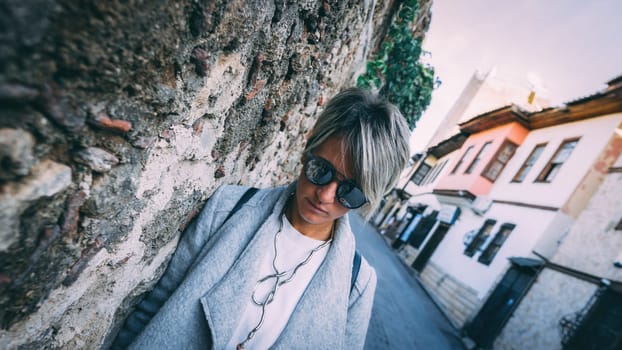 Beautiful blonde adult female standing against wall.